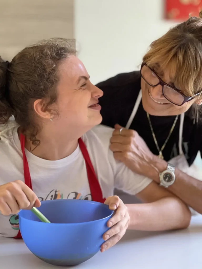 Paola e Melissa si guardano sorridendo mentre preparano una ricetta